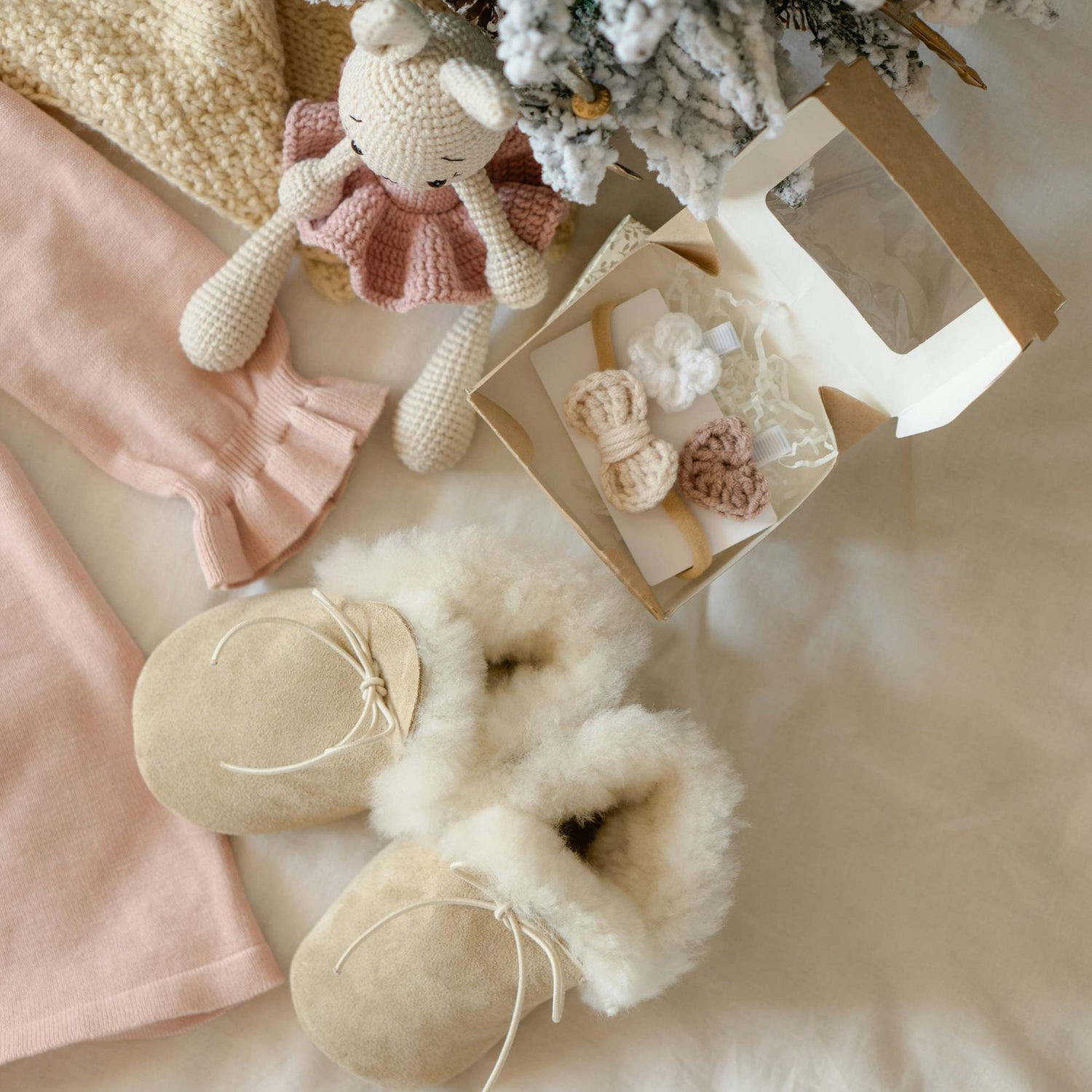 Baby accessories including slippers, a toy, and decorative items on a soft surface presented as a gift bundle.