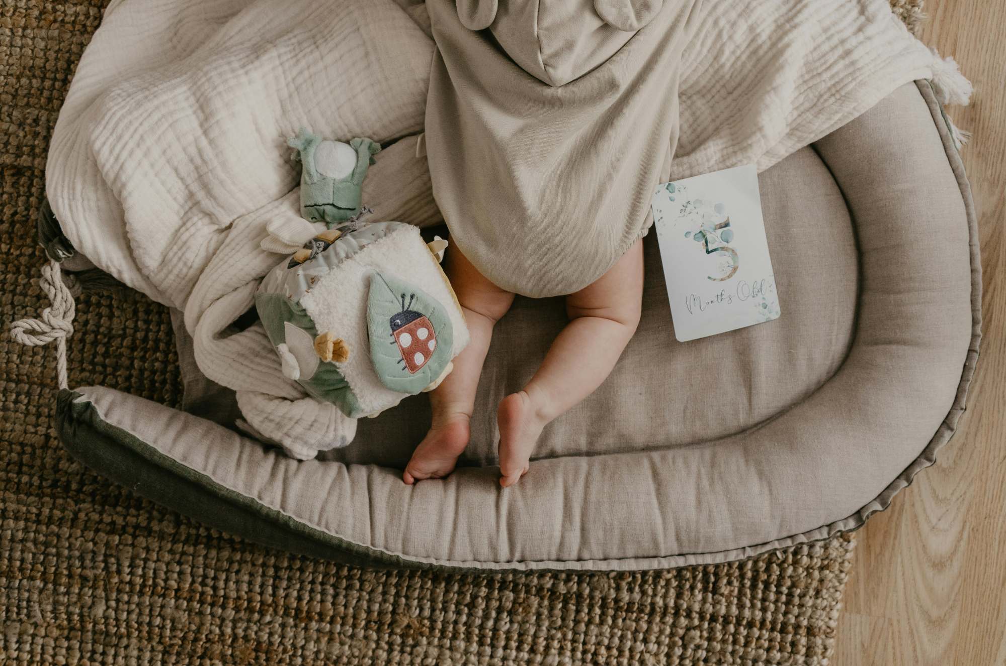 Baby in modern beige linen laying down with soft toys