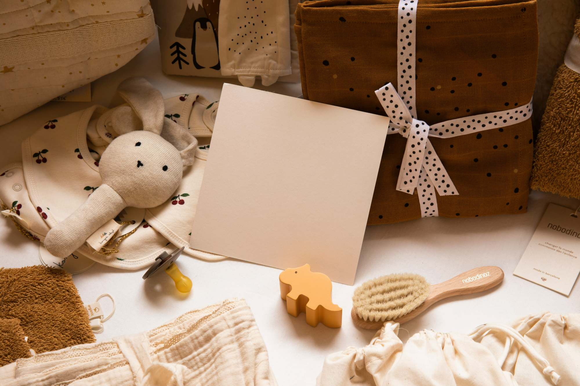 Blank gift note card sitting next to a variety of baby and toddler gifts 