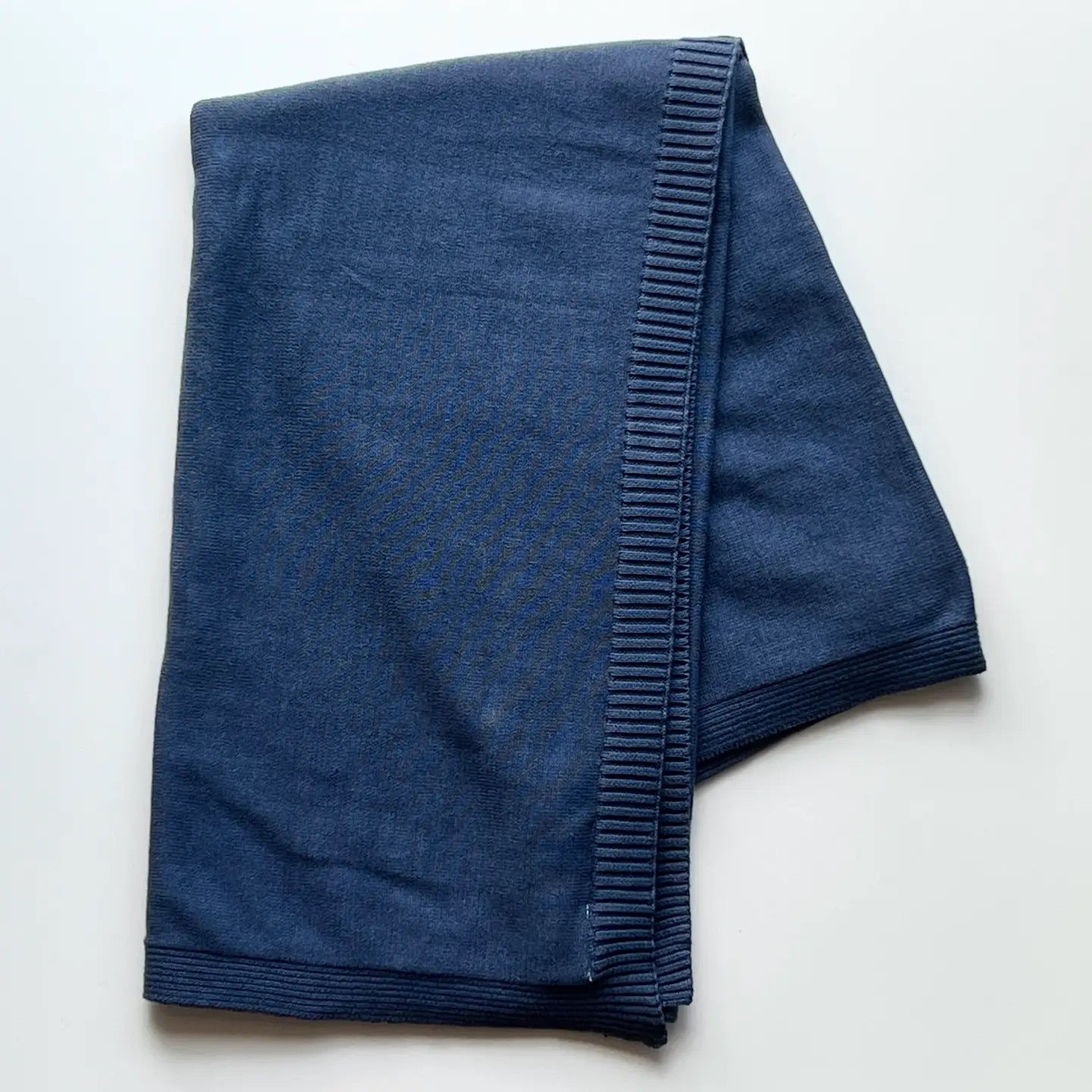 Folded blue baby swaddle blanket on a white background